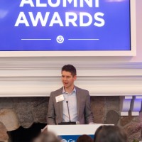 Man looking towards the left as he speaks into microphone